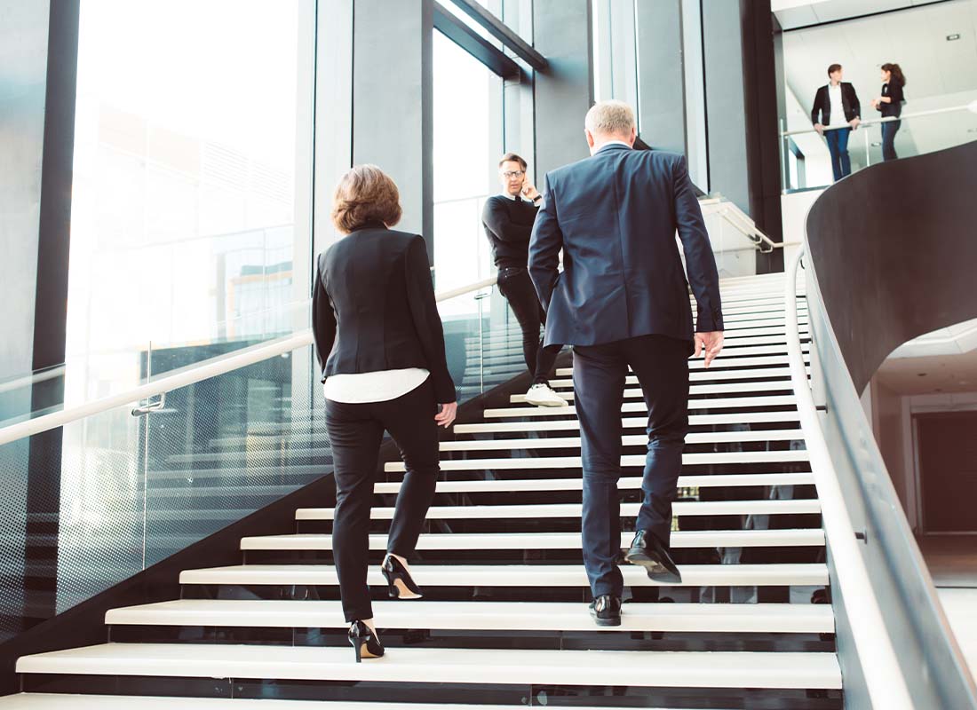 Office Building Insurance - Business Colleagues Walking up the Stairs of a Modern Corporate Office Building in a Large City
