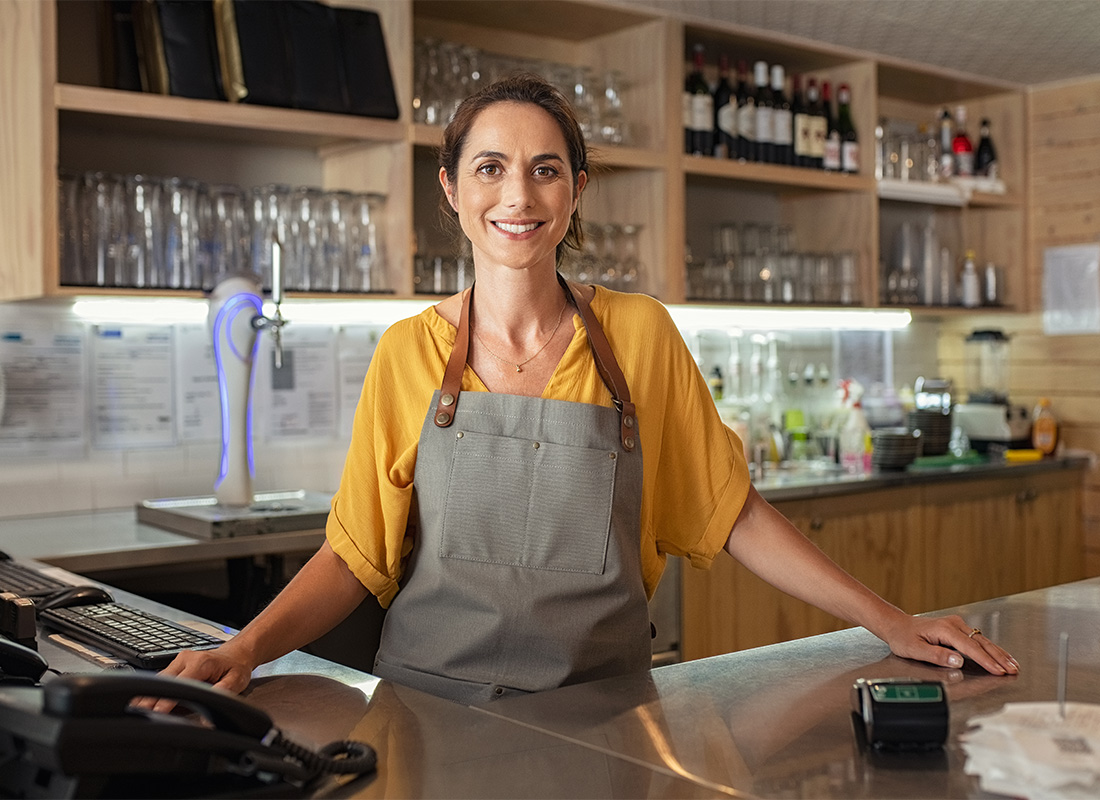Business Insurance - Portrait of a Smiling Young Female Restaurant Owner Standing Behind the Checkout Counter