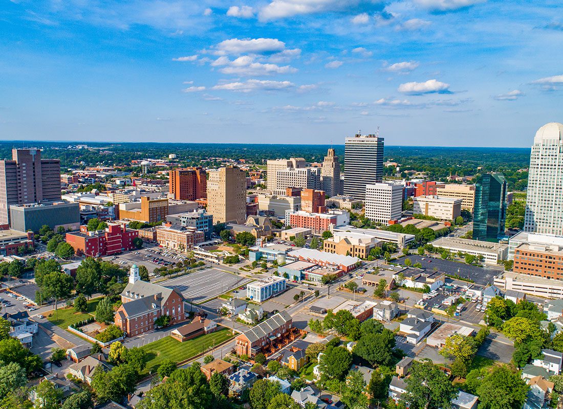 Contact - Aerial View of Downtown Winston-Salem North Carolina Buildings Against a Vivid Blue Sky During the Summer