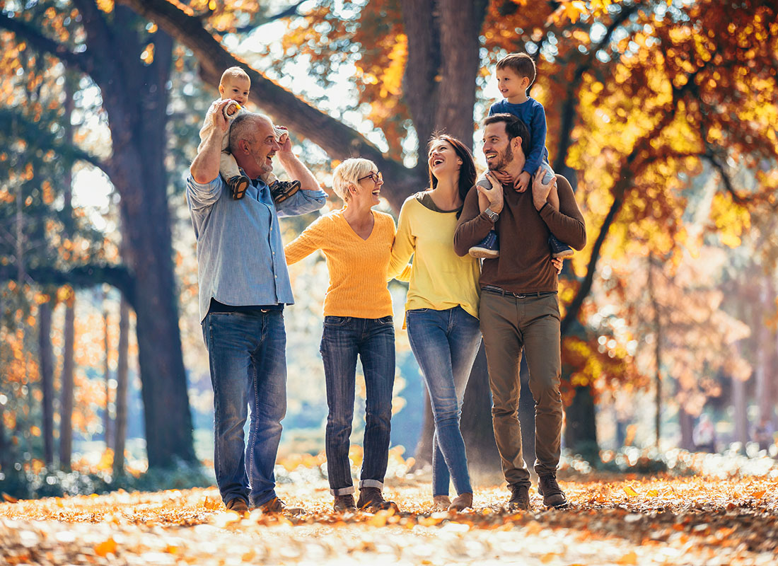 Insurance Solutions - Portrait of a Joyful Extended Family with Two Kids Taking a Walk in the Park on a Sunny Fall Day