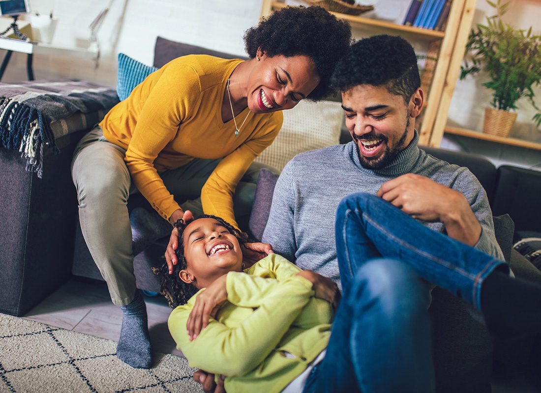 Personal Insurance - Portrait of Joyful Parents Having Fun Playing with Their Daughter in the Living Room